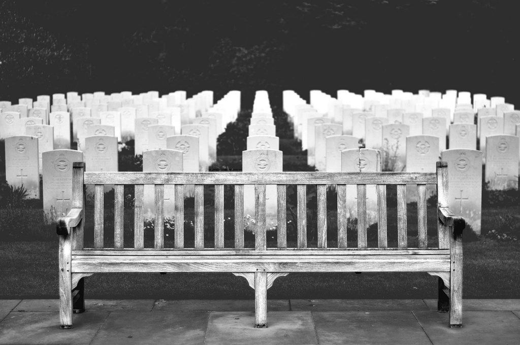 a bench with a group of headstones in front of a cemetery