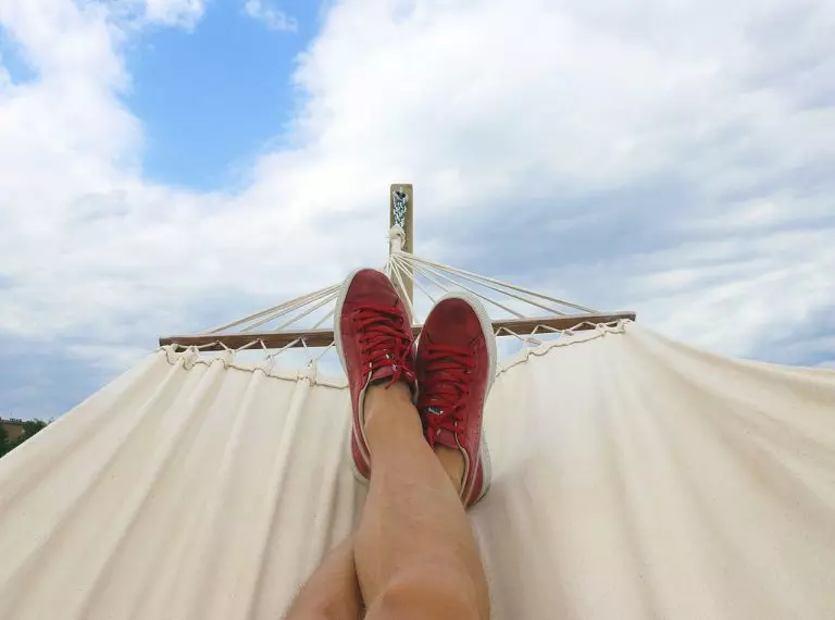 a person's hand with a red nail and a white sand dune with a white building and