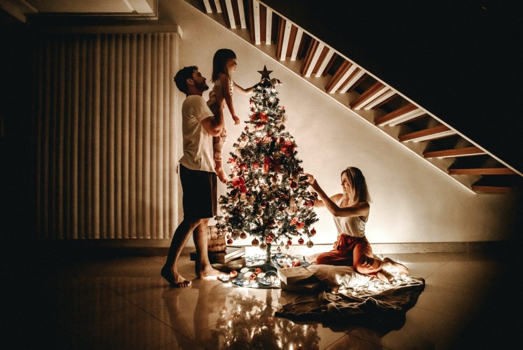 a group of people dancing around a christmas tree