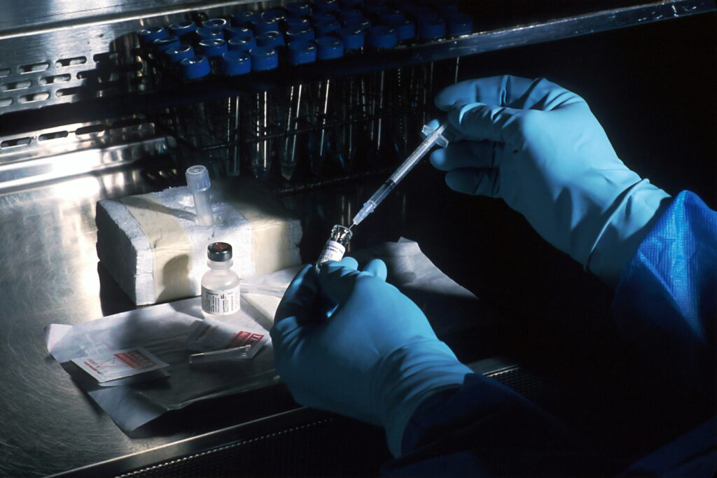 a person wearing gloves and gloves holding a syringe